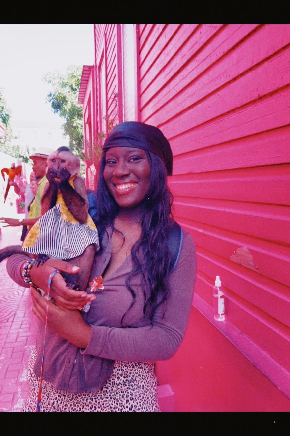 Katrina holding a capuchin monkey in front of a pink building